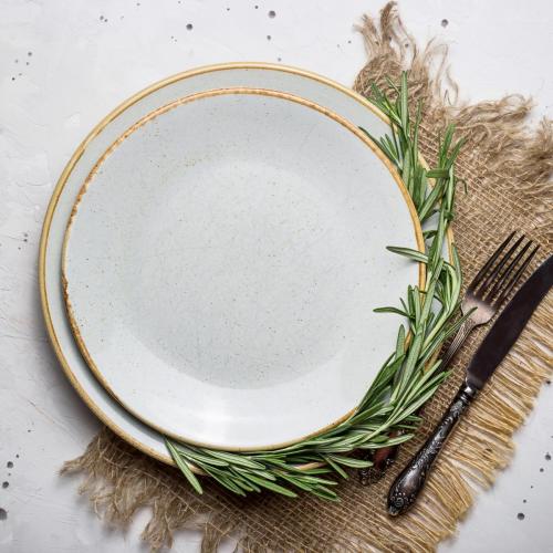 Minimalistic simple rustic table setting with empty plates, fork and knife with burlap napkin and rosemary. Top view, flat lay